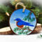 A handmade Christmas ornament with an eastern bluebird hand-painted on a wood slice at Cove Creek Photography.